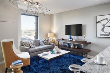 Minneapolis apartment for rent - A living room with a blue carpet and a chair with a wooden seat and back.