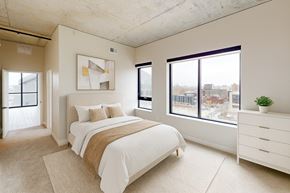 Minneapolis apartment for rent - A bedroom with a large bed and a view of the city.