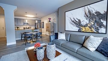 Minneapolis apartment for rent - A modern living room with a grey couch and a large abstract painting on the wall.