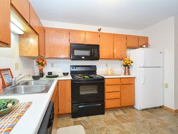 St. Cloud apartment for rent - A kitchen with wooden cabinets and a black stove top oven.