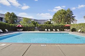 Saint Cloud apartment for rent - A large swimming pool surrounded by lounge chairs and umbrellas.