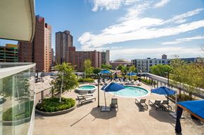 Minneapolis apartment for rent - A vibrant rooftop pool here at LPM Apartments showcasing a spacious sun deck with a sparkling swimming pool, surrounding lounge chairs, and shaded cabanas, set among landscaped greenery and offering elevated city views that create an inviting outdoor space for relaxing, socializing, and enjoying sunny days.