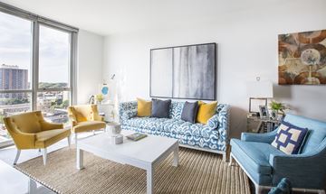 Minneapolis apartment for rent - A living room with a yellow chair, a blue chair, and a white couch with a blue and white patterned cushion.