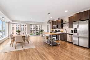 Minneapolis apartment for rent - A modern open-plan kitchen here at Maverick and dining area with wooden floors, dark cabinets, a kitchen island, and a dining set.