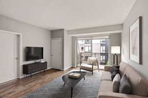 Minneapolis apartment for rent - Modern living room here at Maverick with a beige sofa, patterned rug, coffee table, television on a stand, and balcony view.