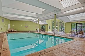 Plymouth apartment for rent - A bright indoor swimming pool here at Plymouth Square featuring a spacious rectangular pool with clear blue water, tiled deck surround, and stainless handrails. The vaulted ceiling with skylights fills the room with natural light, while seating areas and large windows create a relaxing, resort-style atmosphere.