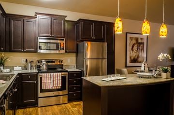St. Louis Park apartment for rent - A kitchen with dark brown cabinets and a stainless steel refrigerator.