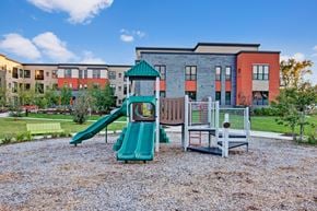 St. Louis Park apartment for rent - A playground with a green slide and a red and grey building in the background.