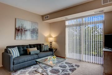 Bloomington apartment for rent - A living room with a black couch and a painting on the wall.