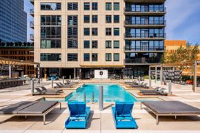 Minneapolis apartment for rent - A resort-style outdoor pool here at The Nic on Fifth featuring a sleek rectangular swimming pool surrounded by modern lounge chairs, shaded pergola seating, and expansive sun decks, with a contemporary high-rise backdrop, private balconies, and an inviting courtyard layout designed for relaxing, socializing, and enjoying city views.