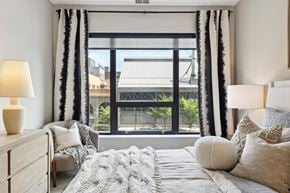 Minneapolis apartment for rent - A bedroom with a large bed and a view of the city through the window.