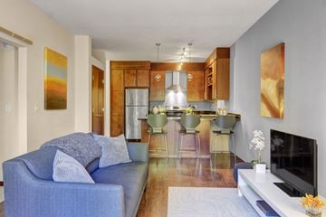 Minneapolis apartment for rent - A blue couch with pillows sits in a living room with a bar and a television.