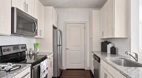 Charlotte apartment for rent - A kitchen with white cabinets and a black stove top.