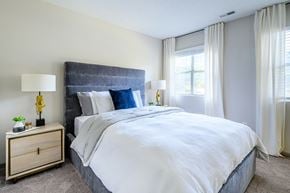 Charlotte apartment for rent - A bedroom with a large bed and a nightstand with a lamp.