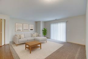 Watford City apartment for rent - A bright living room here at Pheasant Ridge featuring a spacious open layout with a light gray sectional sofa, neutral throw pillows, a wooden coffee table, soft beige area rug, modern wall art, and a sliding glass door that fills the space with natural light and creates a warm, inviting atmosphere.