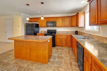 Williston apartment for rent - A kitchen with wooden cabinets and a black refrigerator.