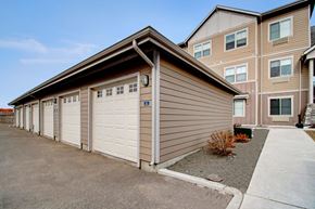 Williston apartment for rent - A building with a brown siding and white garage doors.