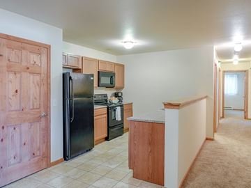 Williston apartment for rent - A kitchen with a black refrigerator and wooden cabinets.