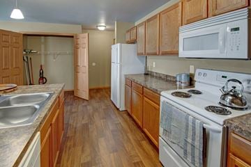 Williston apartment for rent - A kitchen with wooden cabinets and a white stove top oven.