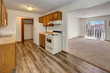 Williston apartment for rent - A kitchen with wooden cabinets and a white stove top oven.