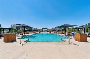 Yukon apartment for rent - A large outdoor swimming pool surrounded by lounge chairs and umbrellas.