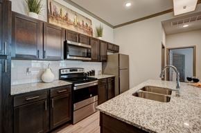 Edmond apartment for rent - A kitchen with dark brown cabinets and a granite countertop.