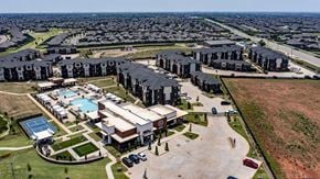 Edmond apartment for rent - A large building complex with a swimming pool in the foreground and rows of houses in the background.