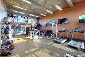 Tulsa apartment for rent - A gym with treadmills, exercise equipment, and a brick wall.
