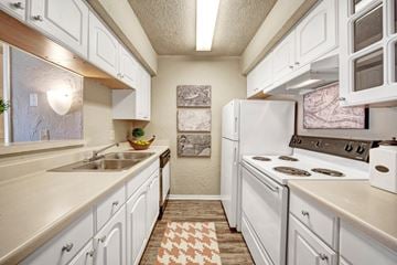 Oklahoma City apartment for rent - A kitchen with white cabinets and a checkered rug on the floor.