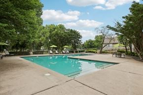 Oklahoma City apartment for rent - A large swimming pool surrounded by trees and lounge chairs.