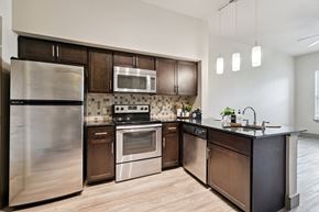 Oklahoma City apartment for rent - A modern kitchen with dark wood cabinets and stainless steel appliances.