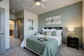 Oklahoma City apartment for rent - A bedroom with a bed, nightstand, and a ceiling fan.