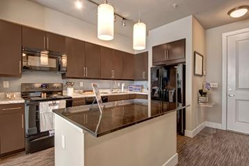 Tulsa apartment for rent - A modern kitchen with brown cabinets and a black countertop.