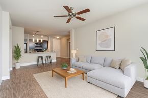 Tulsa apartment for rent - A living room with a white couch, a wooden coffee table, and a ceiling fan.