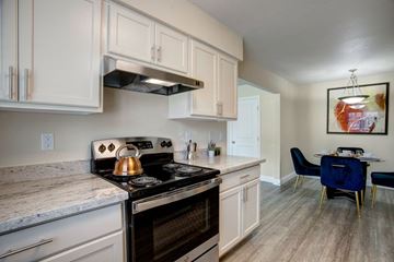 Oklahoma City apartment for rent - A kitchen with a stove top oven and a dining table with chairs.