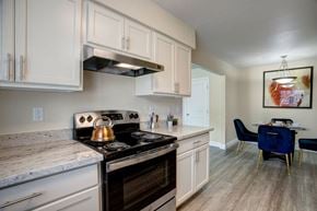 Oklahoma City apartment for rent - A kitchen with a stove top oven and a dining table with chairs.