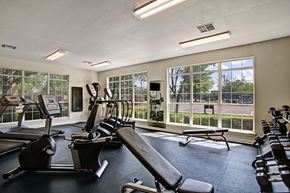 Tulsa apartment for rent - A bright fitness center here at Lincoln Villas on Memorial with large windows, cardio machines, free weights, and a workout bench. A spacious layout with natural light creates an energizing and inviting space for exercise.
