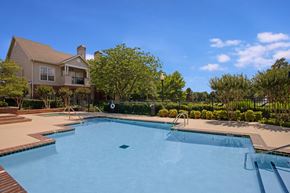 Tulsa apartment for rent - A refreshing pool area here at Lincoln Villas on Memorial with clear blue water, surrounding lounge space, and landscaped greenery. A peaceful setting with nearby buildings and open sky creates a relaxing outdoor atmosphere.