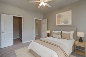 Tulsa apartment for rent - A cozy bedroom here at Lincoln Villas on Memorial with soft carpet, neutral walls, and a ceiling fan with lighting. A spacious closet and warm, inviting layout create a comfortable and relaxing atmosphere.