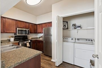 Oklahoma City apartment for rent - A kitchen with brown cabinets and a white door leading to a laundry room.