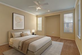 Tulsa apartment for rent - A bedroom here at Memorial Creek with a neutral upholstered bed, white bedding, beige throw blanket, soft carpet, ceiling fan, abstract wall art, and large windows bringing in natural light.