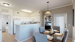 Oklahoma City apartment for rent - A welcoming dining area here at Stoneleigh on May with a glass-top table, upholstered chairs, and pendant lighting. A breakfast bar connects to the kitchen, while a sliding glass door with blinds adds natural light and an open feel.