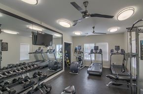 Moore apartment for rent - A spacious gym with a variety of equipment including treadmills, dumbbells, and a television.