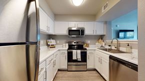 Moore apartment for rent - A kitchen here at Villas at Countryside with white shaker cabinets, stainless steel appliances, bright white countertops, modern hardware, a double sink, and soft overhead lighting creating a clean, inviting look.