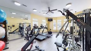 Owasso apartment for rent - A gym with a variety of equipment including treadmills, weights, and a television.
