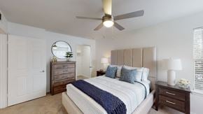 Owasso apartment for rent - A bedroom with a bed, dresser, and ceiling fan.