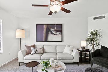 Glendale apartment for rent - A living room with a white couch, a ceiling fan, and a painting on the wall.