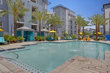 Tempe apartment for rent - A pool surrounded by palm trees and lounge chairs.
