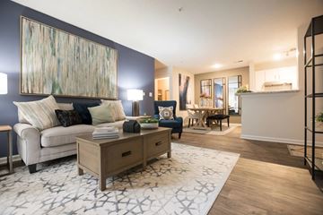 Fort Mill apartment for rent - A modern living room with a white sofa, a wooden coffee table, and a large abstract painting on the wall.