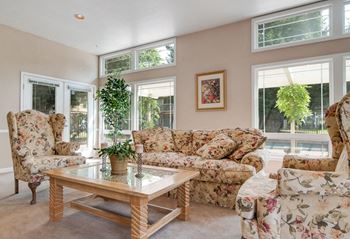 Couches, tables and chairs with large windows overlooking the pool for resident use